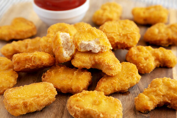 Crunchy Chicken Nuggets with Ketchup on a wooden board, side view.