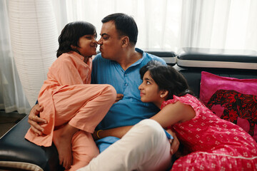 Happy dad having fun with his children on sofa during leisure time at home