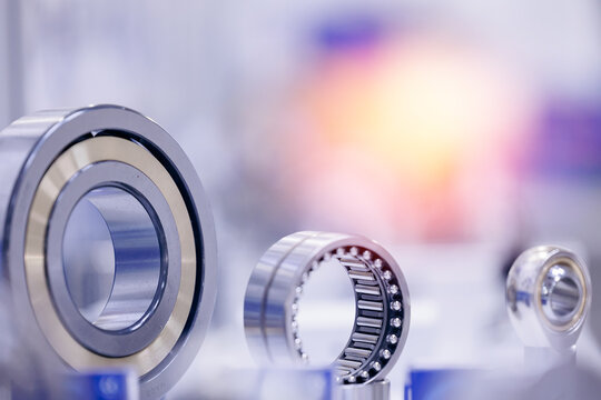 Set of chrome plated round deep roller ball and groove bearings on blur background. Products for heavy CNC equipment and mechanical engineering