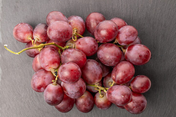 One juicy bunch of grapes on slate stone, macro, top view.
