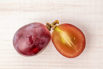 One cut grape berry on a wooden table, macro, top view.