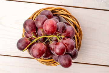 Ripe grapes with vine wreath on wooden table, macro, top view.