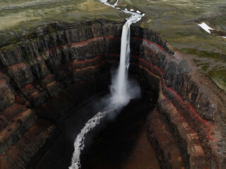 View from above, stunning aerial view of the Hengifoss Waterfall. Hengifoss, is eye-catching due to the striking red clay and black basalt patterns of the cliff face. Fljótsdalshreppur, East Iceland.