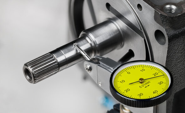 Closeup a yellow dial test indicator with metal probe on hinge and spherical tip. Measuring steel shaft run-out of rotor with 3 vanes in stator of pump compressor by accurate tool on white background.