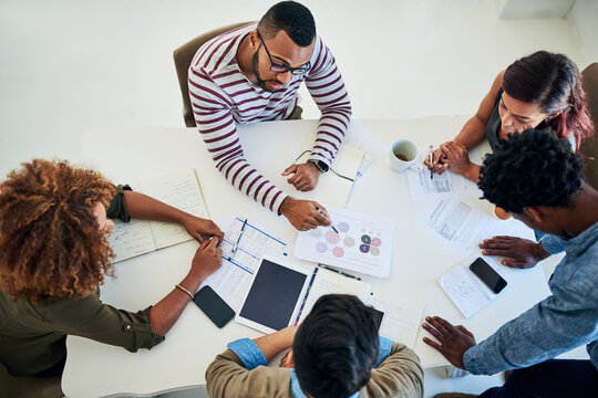 Business people, group and brainstorming in meeting, digital agency and planning for project. Above, employees and graphic designer with documents for feedback, projections for development and review