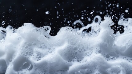 A close-up shot of a foamy wave on a black background, suitable for use in abstract or minimalist designs