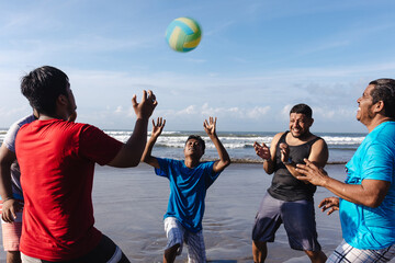 Happy latin group of friends playing volleyball at pacific ocean in Acapulco Mexico Latin America,...