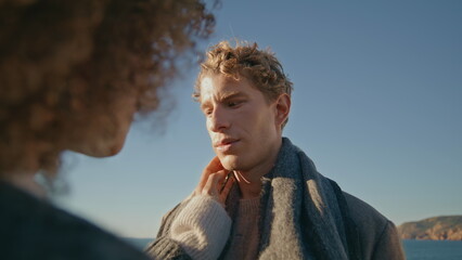 Curly woman touching man face hand at windy seashore closeup. Romantic moment