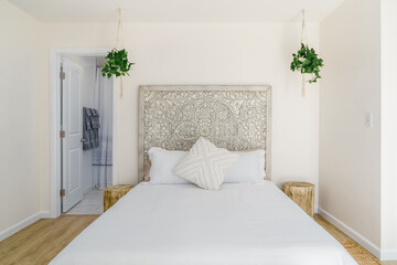 boho modern bed and carved wood headboard and tree stump side table