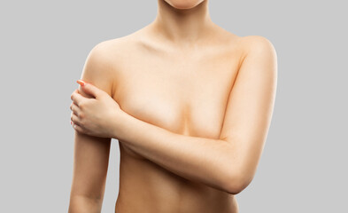 Nude female breast close-up. Sexy slim woman with a naked torso on a white background.The girl makes an examination of the mammary glands for the presence of seals.