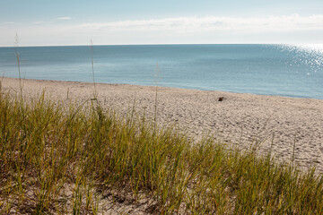 With the protective sand dune grass in the foreground, the calm waters of Lake Michigan at Kohler-Andrae State Park, Sheboygan, Wisconsin reach far out to the distant horizon.