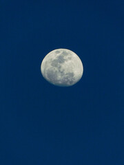 Waning gibbous moon with dark blue sky in the background.