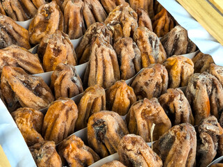 Dried persimmons in a wooden box on a market counter