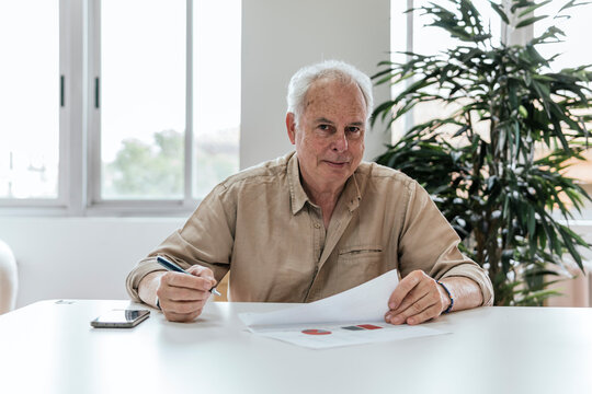 Senior man reviewing documents in bright office