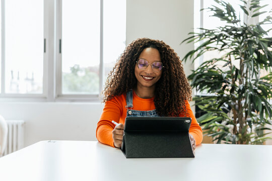 Smiling woman using tablet in bright coworking space - Powered by Adobe