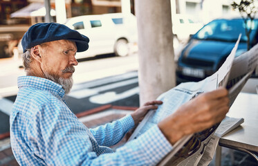 Outdoor, cafe and senior man with newspaper, reading and relax with hobby, knowledge and information. Pensioner, restaurant and old person with gazette, press and tabloid with media in retirement