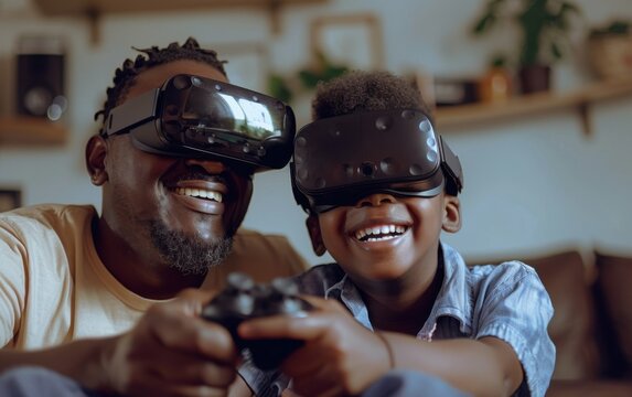 A black father and his son are smiling while wearing virtual reality headsets and playing a video game together in their living room