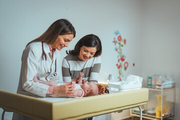 A caring pediatrician attentively examines a newborn, ensuring wellbeing. Both clad in clinic attire, they are surrounded by medical equipment in a well-lit hospital room.