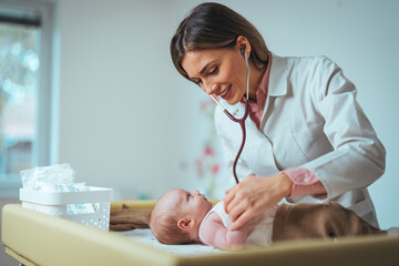 A Caucasian female pediatrician attentively examines a serene newborn baby with her stethoscope in...