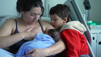 Mother breastfeeding newborn in a hospital bed with older sibling watching, capturing a precious family moment, highlighting the bond and love shared between mother, baby, and sibling