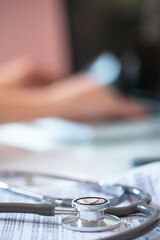 Stethoscope on doctor's prescription on background of specialist's hands working on laptop. Vertical photo