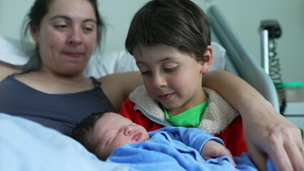 Mother watches lovingly as older sibling cradles newborn baby, highlighting the tender bonds of family love, affection, and the nurturing connection between siblings in a heartfelt moment