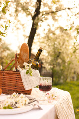 Stylish table setting with beautiful spring flowers and wine in garden
