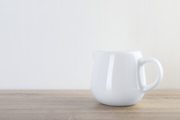 Jug of fresh milk on wooden table, space for text