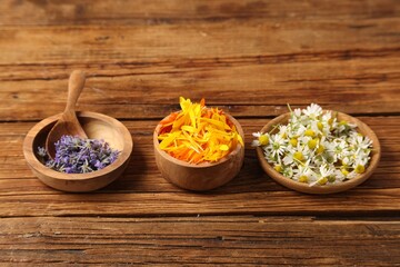 Different flowers in bowls and spoon on wooden table