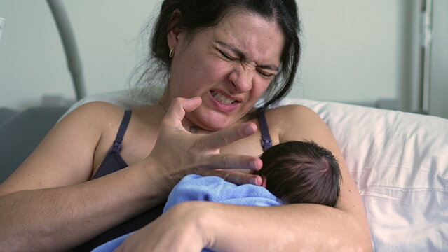 Older sibling leaning against the hospital bed, observing mother wincing in pain, highlighting the challenges and raw emotions of early motherhood in a hospital setting