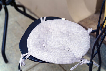 soft gray round chair cushion, tied to a chair, adding comfort and style to any seating arrangement...