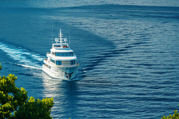 Large luxury private motor white yacht sailing in sea with bow wave wide shot