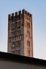 The San Frediano church tower with intricate windows against a clear blue sky at sunset