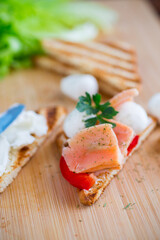 fried toast with salmon, cream cheese, salad, on a wooden table