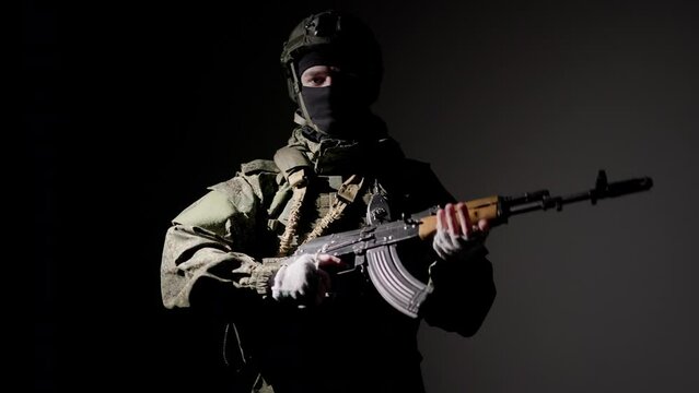 Military soldier stands in dark with rifle