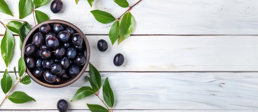 Jamun in a Bowl with Leaves on White Wooden Background with Copy Space