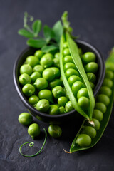 Green sugar snap peas in a bowl on black background close up. Green pea beans vegetables. Food photography