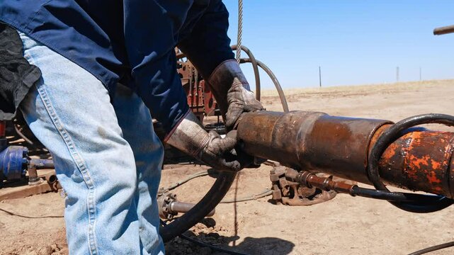 Unrecognized man in dirty gloves disassembles the parts from the pipe. Worker maintaining the equipment for drilling gas and oil.