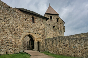 Točník Castle rises against a dramatic cloudy sky, its medieval architecture enhanced by the moody atmosphere.