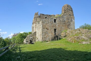 Hrad Přimda stands tall atop a hill, its ancient ruins glowing under a bright blue sky on a summer day.
