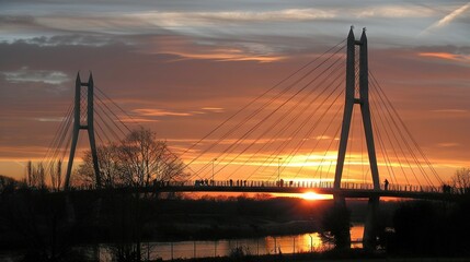 Obraz premium A bridge silhouette spans over water at dusk as a person stands on the opposite bank, framed by vibrant hues
