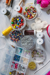 Creating Christmas ornaments. Handcraft artist workspace. Laptop, colorful beads, felt, tools, scissors, needles, thread spools, glue, containers, pliers, wire. Creative chaos concept. Flat lay.