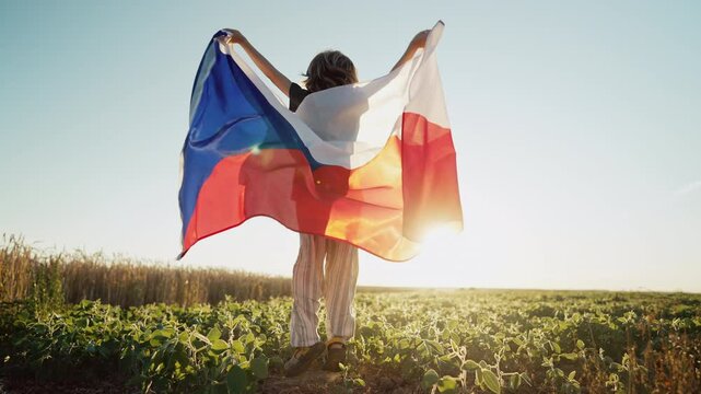 Czech little kid - patriot child boy jumps with national flag on nature background at summer sunset. Cestina celebration banner, holidays in Czechia