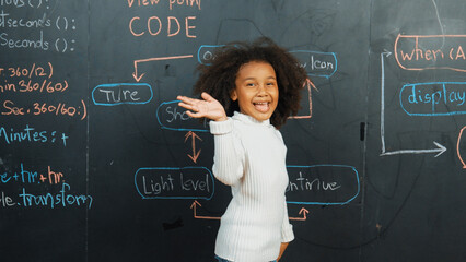 Happy african girl writing blackboard and turnaround to waving at camera while standing at board...