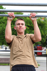 Naklejka premium Teenager 16 years doing workout on horizontal bar, outdoor sport, young sportsman, healthy life concept