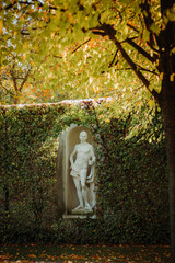 statue stands in an alcove of a vine-covered wall in a park in Vienna, Austria
