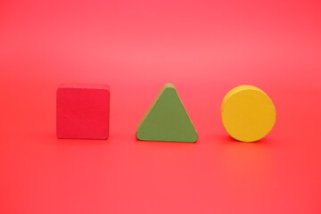 colorful wooden toys isolated red background. wooden toys shaped like triangles, squares and circles.