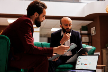 Fototapeta premium Team discuss different business practise in the heart of international conference at hotel resort lounge area. Coworkers creating new partnership together, sharing ideas for development.