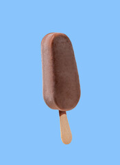 Chocolate popsicle ice cream on a stick, isolated on a blue background.