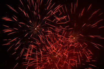 Several red colored firework explosions in open night sky